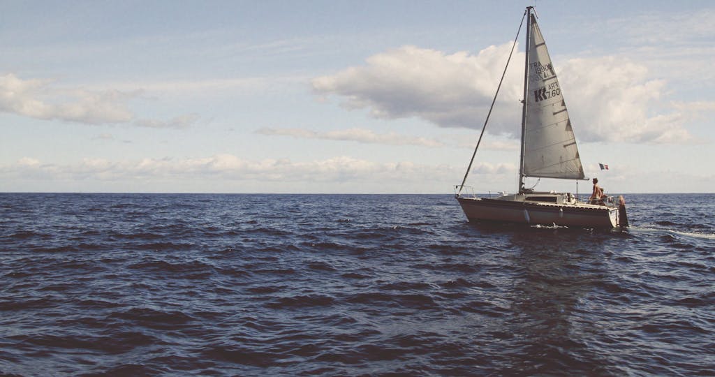 Sailboat under sail on open water with cloudy sky